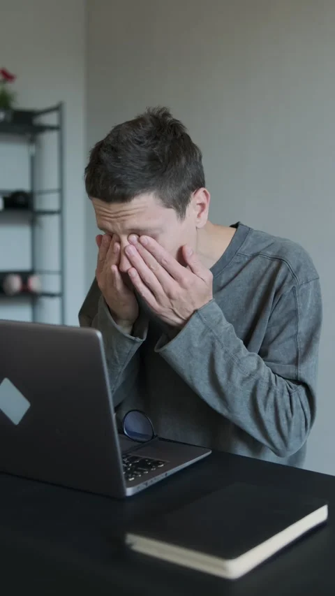 Close-up of tired man at home taking off glasses rubbing eyes while sitting at Stock Footage 308961897