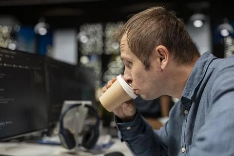 Close up of tired programmer drinking coffee in AI startup office, taking break Stock Photos