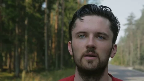 Close-up of tired runner of marathon running down the road near a forest Stock Footage 74552979