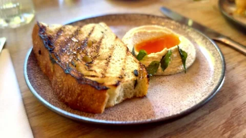 Close up of toasted bread with side of hummus herbs and chili sauce appetiser Stock Footage 335894255