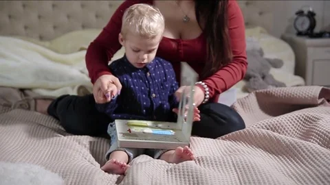 Close up of toddler browsing a book with his pregnant mum. FULL HD. SLOW motion Video stock 73976153