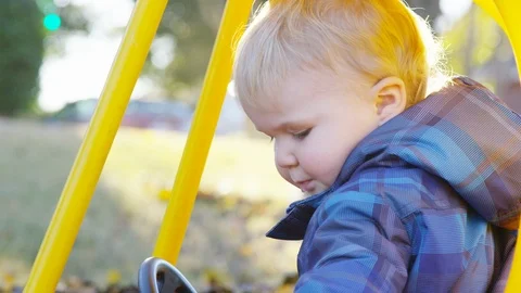 Close on Toddler getting inside toy car as leaves fall around him Stock-Footage 93890571