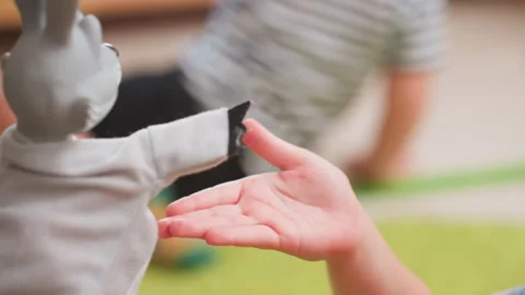 Close Up Toddler Hand Reaching for Puppet Touch in Classroom Stock Footage 322541345
