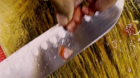 Close Up of Tomato Being Cut into Small Sections on Wooden Cutting Board Stock Footage 346744840