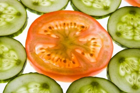 Close-up of tomato slice surrounded by cucumbers Stock Photos