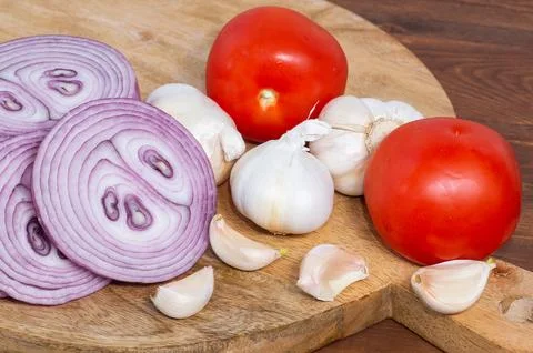 Close-up of tomatoes, garlic, and red onion on a wooden background. Foto stock