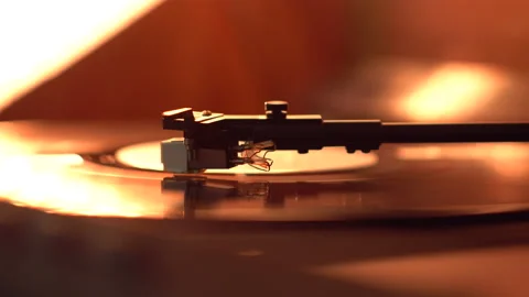 Close up of a  tone arm and spinning vinyl record lit with warm light. Stock Footage 154805612