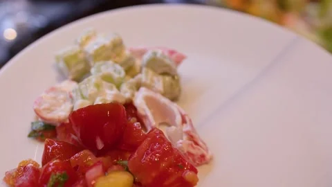 Close Up of Tongs Serving Fresh Salad onto a White Plate Stock Footage 336935976
