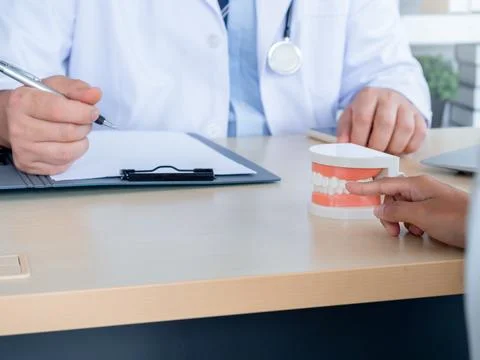 Close up a tooth model on desk while dentist make writing with a patient fi.. Stock Photos