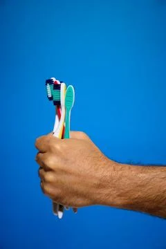 Close-up of toothbrushes of different colors and blue background Stock Photos