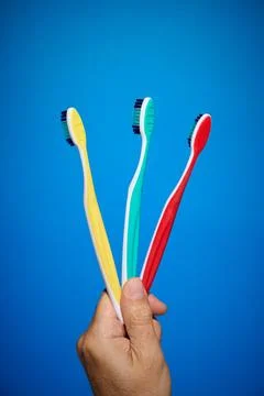 Close-up of toothbrushes of different colors and blue background Stock Photos