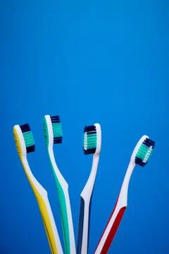 Close-up of toothbrushes of different colors and blue background Stock Photos