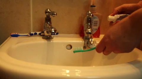 Close up of toothpaste being applied onto toothbrush in front of a sink. Stock Footage 247125658