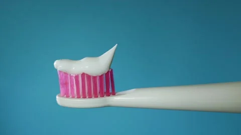 Close-up of toothpaste being squeezed onto a pink toothbrush head Stock Footage 340264237