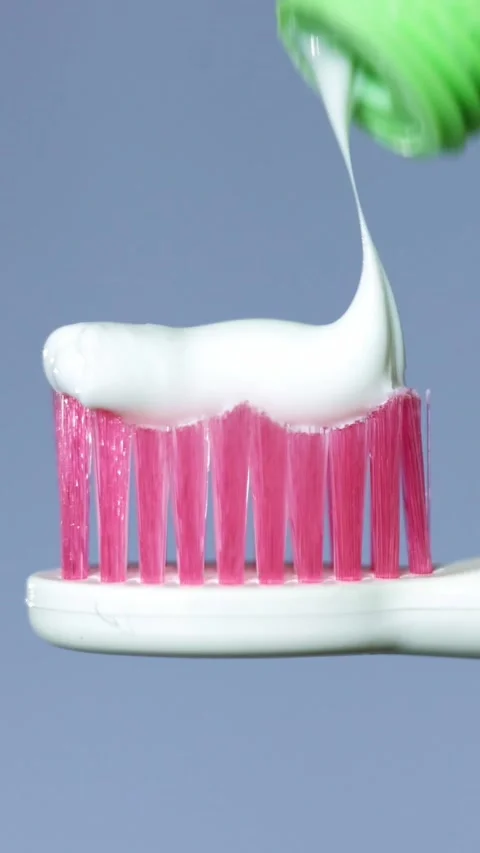 Close-up of toothpaste being squeezed onto a pink toothbrush head Stock-Footage 343838105