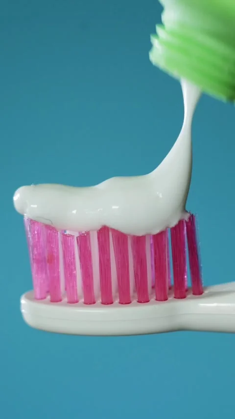 Close up of toothpaste being squeezed onto a pink toothbrush for dental hygiene Stockbeeldmateriaal 343838116