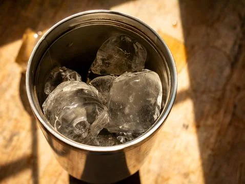 Close-up top angle view into stainless steel tumbler cup with melting ice c.. Foto stock