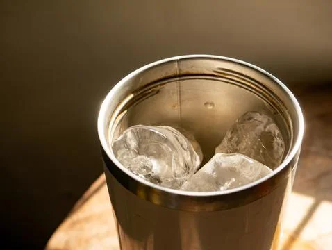 Close-up top angle view into stainless steel tumbler cup with melting ice c.. Stock-Fotos