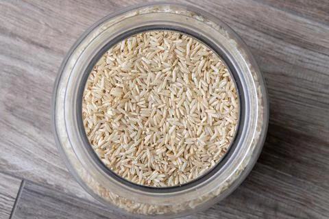 A close up top down portrait of a glass pot full of rice standing on a wooden Foto stock