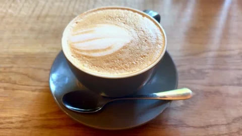 Close up top down view of coffee cup on saucer with teaspoon on wooden table Stock Footage 335827443