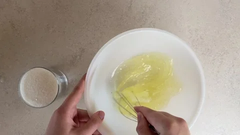 Close-up top-down view of hands using a whisk to beat raw egg whites in a p.. Stock Footage 320955281