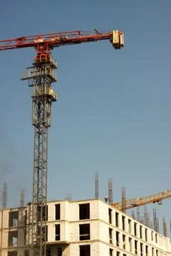 Close-up of the top of a red tower crane near a new building against a blue s Stock Photos