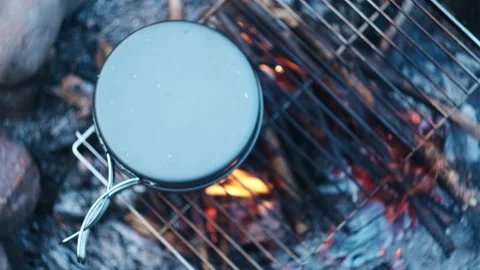 Close-up top view of black pot above beautiful calm campfire at evening time Stock Footage 247316536