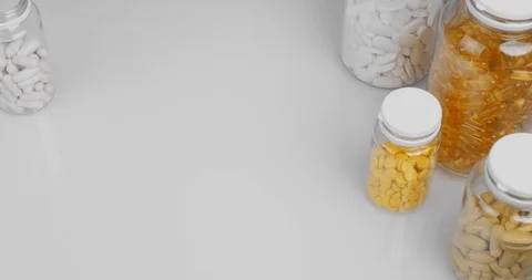 Close-up top view bottles orange gel capsules, pills white background Stock Footage 126328212