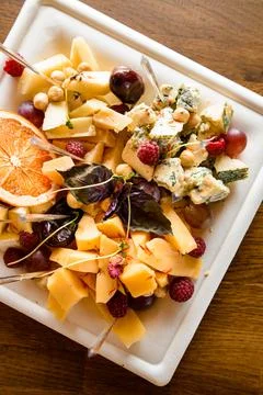 Close-up top view of cheese snacks and nuts and berries on white square plate Stock Photos