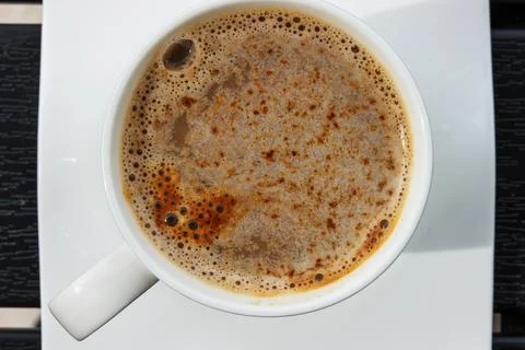 Close up top view of coffee cup on a square white saucer, placed on a dark .. Фото