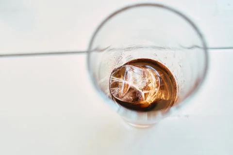 Close up top view of cola drink with single ice cube in glass container Stock Photos