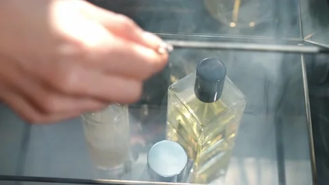Close-up top view cologne bottles in aromatic smoke with female slim young hand Stock Footage 221864178
