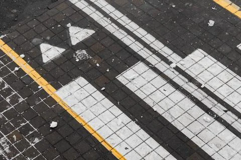 A close-up top view of a dark tiled sidewalk featuring bold white arrows an.. 写真素材