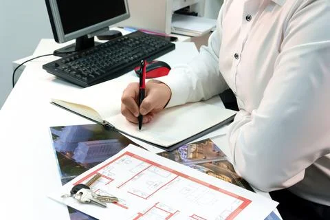 Close-up, top view, desk at which an impersonal man sits making work notes in a Stock Photos