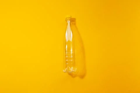 Close-up top view of empty transparent plastic bottle on yellow background. Stock Photos