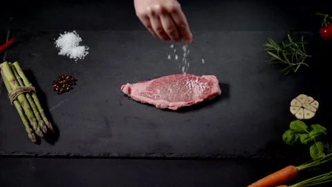 Close Up Top View Of Female Applying Salt And Rosemary Herbs On Piece Of Steak Stock Footage 170241345