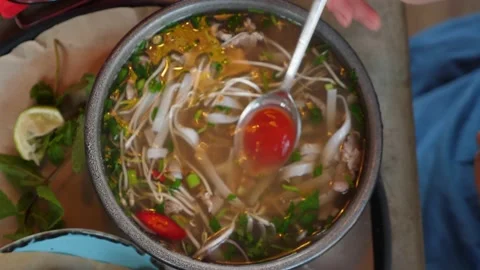 Close-up top view. female hands add sauce to a bowl of pho bo soup Stock Footage 160409899