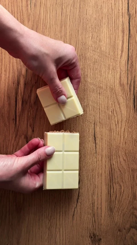 Close-up top view of female hands breaking a white chocolate bar with nut f.. Stock Footage 330956195
