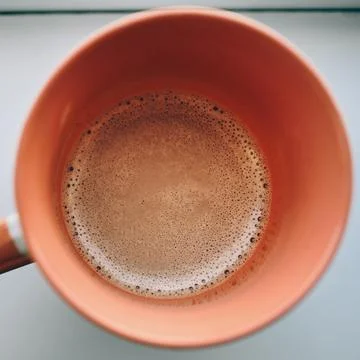 A close-up top view of freshly brewed hot coffee with rich crema in an oran.. Stock Photos