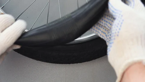 Close-up top view of a gloved hand mounts a new camera on a bicycle wheel tire. Stock Footage 115126237