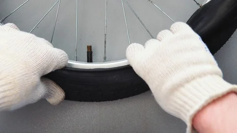 Close-up top view of a gloved hand mounts a new camera on a bicycle wheel tire. Stock Footage 115126259