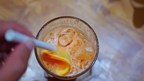 Close-up, top view, a hand holds a straw, a man stirs a cocktail with orange Stock Footage 243458741
