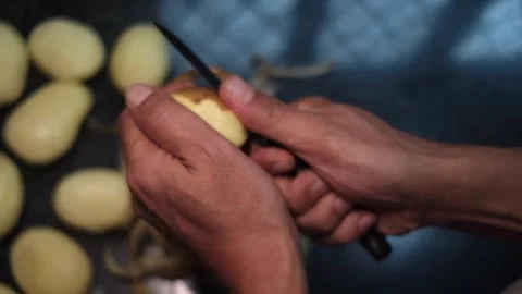 Close up top view of hands peeling raw fresh a potato with a knife. Stock Footage 247546619