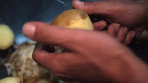 Close up top view of hands peeling raw fresh a potato with a knife. Stock Footage 249278585