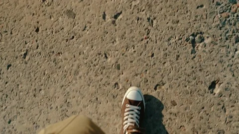 Close-up top view of the legs of a man walking on a concrete road. Stock Footage 202609147