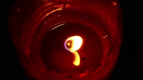 Close-up top view of a lit red candle with flaming fire in the dark of a Stock Footage 164572090