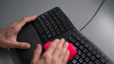 Close-up top view of male hands cleaning dusty black ergonomic computer keyboard Stock Footage 342763988