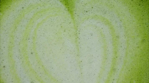 Close up top view of matcha latte foam with heart shaped latte art pattern. Stock Footage 336346305