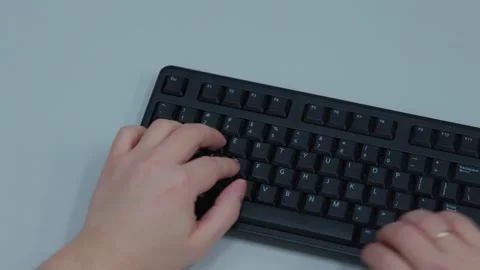 A close-up top view of a person is typing on a keyboard Stock Footage 300749577