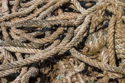 Close-up top view of a pile of old, weathered, and tangled thick nautical ropes Stock Photos